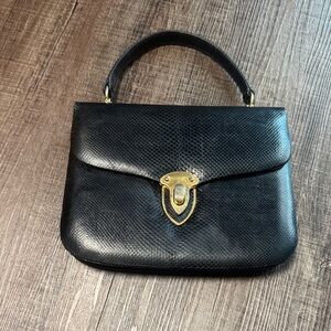 Finesse La Model Embossed black Leather Hand Bag with Gold clasp.